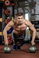 Man doing push-up exercise with dumbbell photo