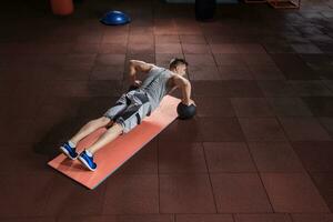 Attractive male athlete performing push-ups on medicine ball photo