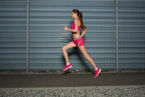 corriendo mujer. trotar en contra el antecedentes de un gris pared foto