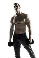 Strong athletic man showing muscular body with dumbbells photo