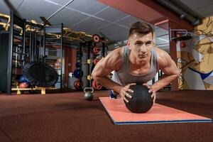 Attractive male athlete performing push-ups on medicine ball photo