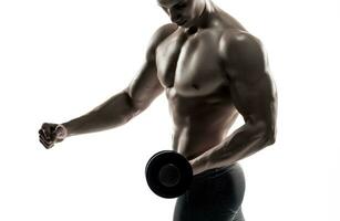 atlético hombre demostración muscular cuerpo y haciendo ejercicios con pesas foto