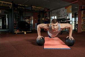 Attractive male athlete performing push-ups on medicine ball photo