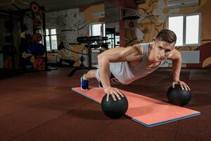 Attractive male athlete performing push-ups on medicine ball photo