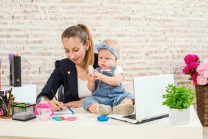 mamá y mujer de negocios trabajando con ordenador portátil computadora a hogar y jugando con su bebé muchacha. foto