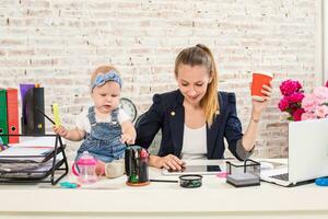 mamá y mujer de negocios trabajando con ordenador portátil computadora a hogar y jugando con su bebé muchacha. foto