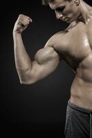 aptitud hombre demostración su tríceps, bíceps músculos en negro antecedentes foto
