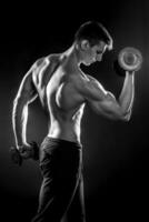 Man with naked torso and dumbbells on black background photo