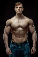 Muscular bodybuilder guy doing posing over black background photo