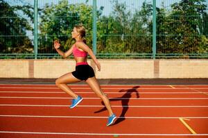 Side view beautiful young woman exercise jogging and running on athletic track on stadium photo