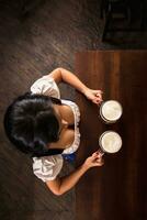 Oktoberfest. Brunette woman holding beer mugs in bar. Top view photo