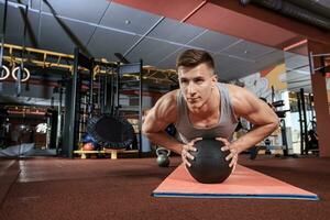 atractivo masculino atleta ejecutando Lagartijas en medicina pelota foto