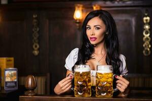 Oktoberfest. Brunette woman holding beer mugs in bar photo