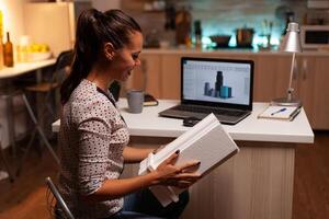 Female architect looking at building model during late night time in home office. Engineer artist creating and working in office holding scale building model, determination, career. photo