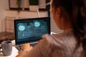 Woman doing cyberspace criminal activity hacking firewall using laptop from home office at night time. Programmer writing a dangerous malware for cyber attacks using performance laptop during midnight. photo