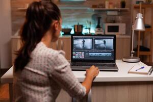 Back view of creative filmmaker working on a movie on laptop during midnight. Content creator in home working on montage of film using modern software for editing late at night. photo