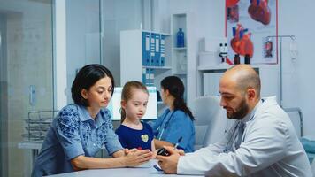 médico participación pastillas botella y escritura instrucciones mientras hablando con padre en clínica. médico, especialista en medicina Proporcionar salud cuidado servicios consulta diagnóstico tratamiento en hospital foto