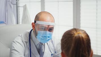 Close up of doctor with visor checking temperature. Physician specialist in medicine with mask providing health care services consultation treatment examination in hospital cabinet during covid19 photo