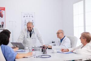 Radiologist doctor in white coat standing at desk discussing research expertise in conference meeting room. Medical hospital team presenting healthcare examination explaining health treatment photo