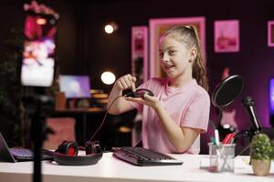 Generation Z online star in studio reviewing gaming mouse in front of professional camera in studio. Smiling kid filming electronics haul, showcasing wired RGB lit computer peripheral to audience photo