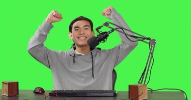 POV of content creator on live stream recording gameplay of new action video game launched, greenscreen backdrop. Asian streamer broadcasting multiplayer competition, streaming with microphone. photo