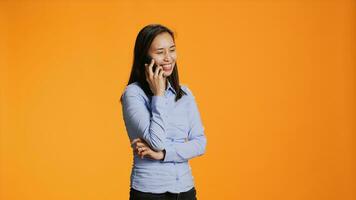 Casual adult receiving phone call in front of camera, chatting with friends on smartphone telecommunications network. Asian girl answering telephone for remote discussion in studio. photo