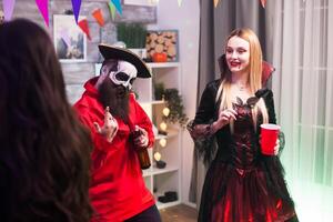 Man dressed up like a pirate singing at halloween celebration with his friends. photo