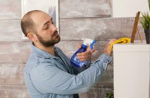 Young man cleaning dust of furniture in home. photo