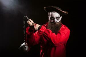 Spooky male pirate with long beard holding a mace over black background. Halloween outfit. photo