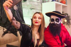 Cheerful pirate and vampire woman at halloween party taking a selfie. photo