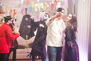 Cheerful man and woman dressed up like a witch and zombie for halloween party. photo