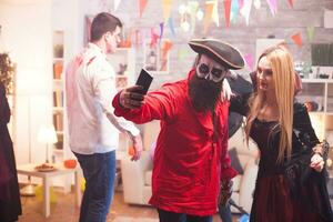 Couple dressed up like a pirate and vampire taking a selfie at halloween party. photo