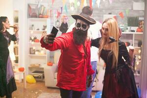 Blond vampire woman taking a selfie with a medieval pirate at halloween celebration. photo