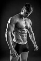 Muscular bodybuilder guy doing posing over black background photo