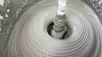 miscelazione cemento mortaio con un' miscelatore nel un' secchio avvicinamento, struttura di misto mortaio. preparazione di costruzione miscela. il concetto di automazione di Manuale lavoro duro e faticoso nel costruzione. video