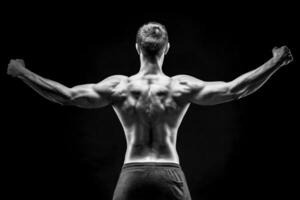 Rear view of muscular young man showing back, biceps muscles photo