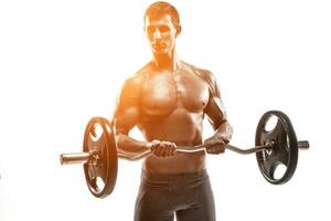 Young handsome man with naked torso and barbell photo