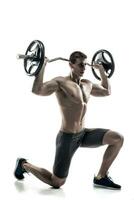 Mighty man standing on knee and holding barbell photo