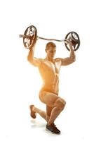 Muscular man standing on knee, holding barbell over his head photo
