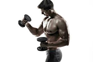 Athletic man showing muscular body and doing exercises with dumbbells photo