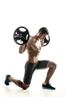 Muscular man standing on knee, holding barbell over his head photo