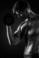 Muscular man working out doing exercises with dumbbells at bicep photo