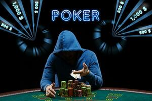 Man in blue hoodie showing aces, sitting at playing table with stacks of chips. Black background with neon dollar amounts, inscription poker. Casino photo