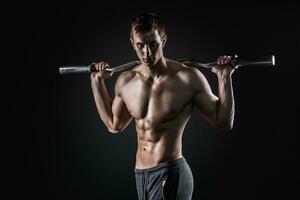 Strong man holding barbell on his shoulders, looking at camera photo