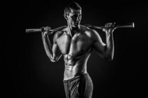 Strong man holding barbell on his shoulders, looking to side photo