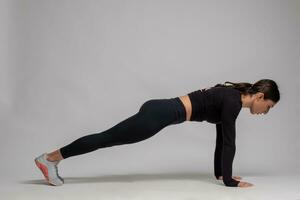 Girl standing in plank on straight arms on grey background photo