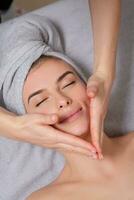 Beautiful young woman getting facial massage in spa salon. Beauty treatment concept. photo