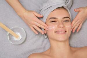 Beautiful young woman getting facial massage in spa salon. Beauty treatment concept. photo