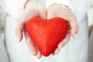 rojo corazón símbolo en el manos de un médico foto