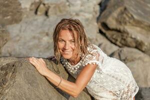 beautiful blond woman wearing a white shirt posing on a rock photo